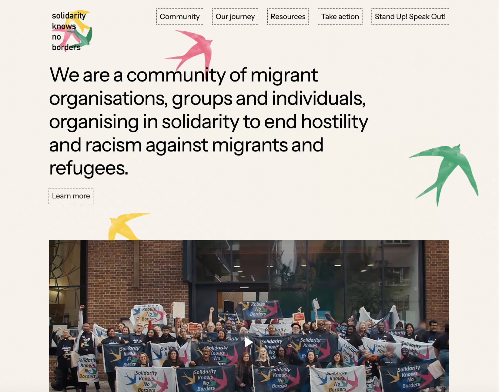 Homepage of “Solidarity Knows No Borders” showing a group photo of activists holding banners in front of a building. Large text at the top reads, “We are a community of migrant organisations, groups and individuals, organising in solidarity to end hostility and racism against migrants and refugees.” Colorful flying bird graphics appear around the page.